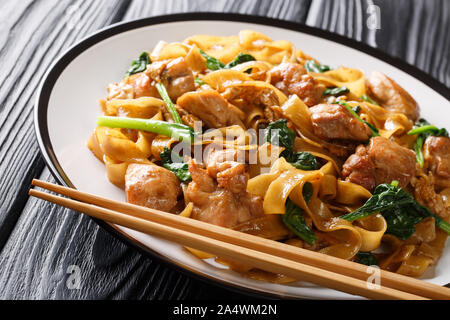 Voir pad Thaï au poulet nouilles de Ge, le brocoli chinois et des oeufs sur une plaque horizontale sur la table. Banque D'Images