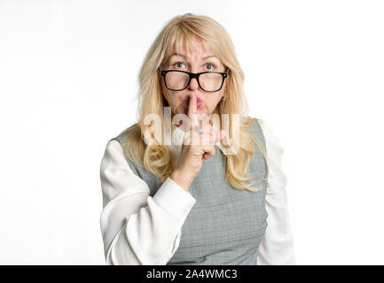 Au calme ! Femme debout dans les verres montre un geste de silence sur un fond clair. Gardez votre doigt près de la bouche. Banque D'Images