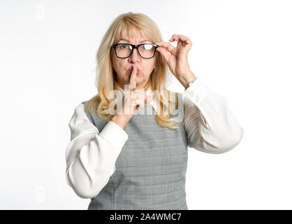 Au calme ! Femme debout dans les verres montre un geste de silence sur un fond clair. Gardez votre doigt près de la bouche. Banque D'Images