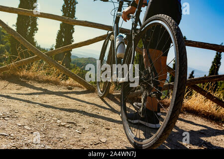 Low angle d'un cycliste masculin debout avec son vélo avant ou après l'entraînement à regarder la vue Banque D'Images