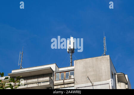 La communication cellulaire des antennes sur un toit d'un bâtiment résidentiel à plusieurs étages contre le ciel bleu. Low angle view. Banque D'Images