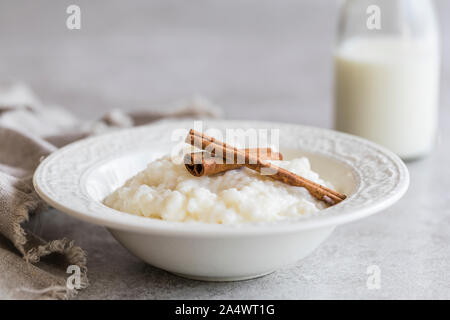 Riz au lait à la cannelle et une bouteille de lait. Tourné sur un fond gris avec copie espace. Banque D'Images