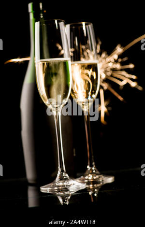 Deux verres de champagne et une bouteille en face de d'artifice sur fond noir Banque D'Images