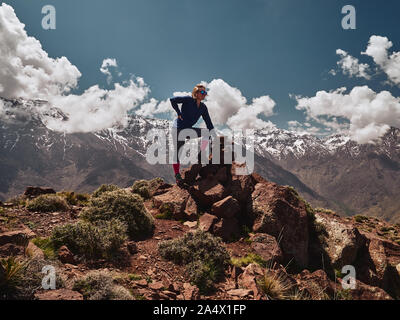 Caucasian blonde Girl standing tourisme en haut de la montagne Jebel Tooubkal avec en arrière-plan, le Maroc, l'Afrique Banque D'Images