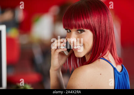 Confident female designer parler sur un téléphone mobile en rouge creat Banque D'Images