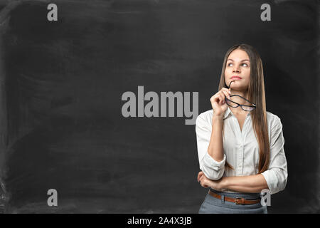 Young businesswoman standing in front of blackboard blank Banque D'Images