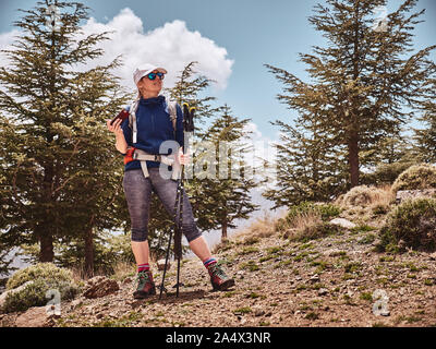 Backpacker touristiques girl navigation dans la haute montagne forêt avec son smartphone Banque D'Images