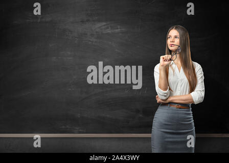 Young businesswoman standing in front of blackboard blank Banque D'Images