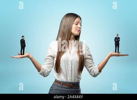 Woman holding businessman à petite échelle sur chaque main outstreched Banque D'Images