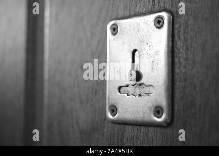 Porte en bois avec trou de chrome et de la lumière du soleil, photo en noir et blanc. Banque D'Images