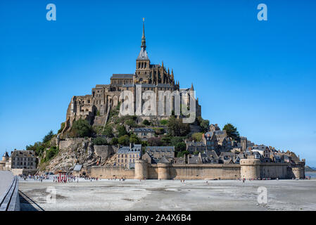 Abbaye du Mont Saint Michel à marée basse et touristes se rendant sur elle. Banque D'Images