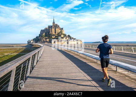 Homme qui court sur la seule route d'accès au Mont Saint Michel. Sur pied est l'une des options autorisées pour l'accès. Banque D'Images