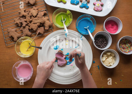 Young Girl decorating gingerbread avec glaçage sur une plaque Banque D'Images