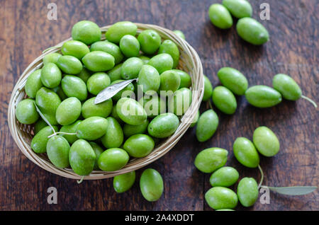 Olives vertes dans le panier en osier sur la table. Vue d'en haut. Banque D'Images