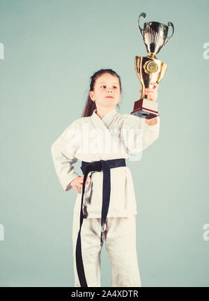 De souligner leurs réalisations. Le karaté donne un sentiment de confiance. Kid forte et confiante. Petit enfant fille en kimono blanc avec ceinture. Karate fighter enfant. Karate sport concept. Compétences d'auto-défense. Banque D'Images