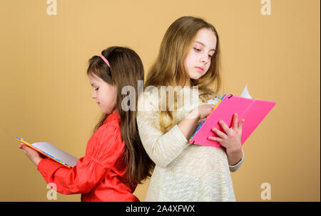 Heureux les petits enfants prêts pour l'école leçon. Amitié et fraternité. de cahiers d'écriture. Retour à l'école. Les élèves de lire un livre. Projet d'école. les petites filles avec note books. La vérification des résultats. Banque D'Images