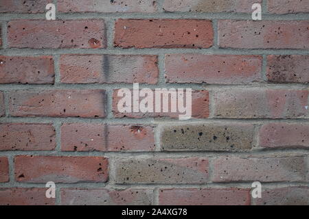 Vue de face d'un mur de brique rouge, moderne avec des dommages d'usure. Banque D'Images