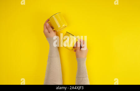 Deux tasses en céramique jaune sont pris en charge par une femme part sur un fond jaune, copy space Banque D'Images