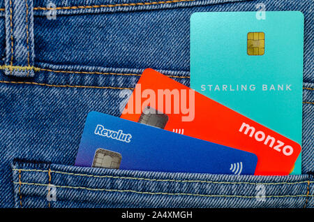 L'Monzo, Revolut Starling et cartes bancaires coller à partir de la même poche de jeans. Concept pour un concours sur l'aileron, tech. Photo mise à plat. Banque D'Images