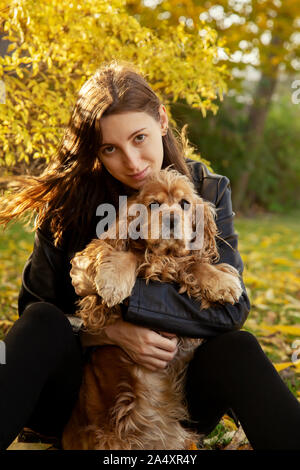 Femme avec cocker américain joue à autumn park Banque D'Images