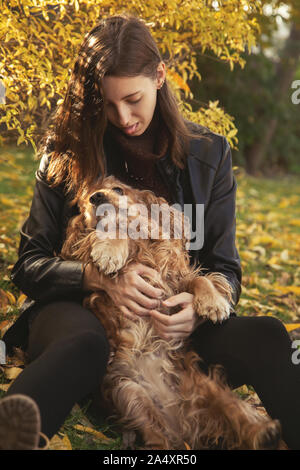 Femme avec cocker américain joue à autumn park Banque D'Images