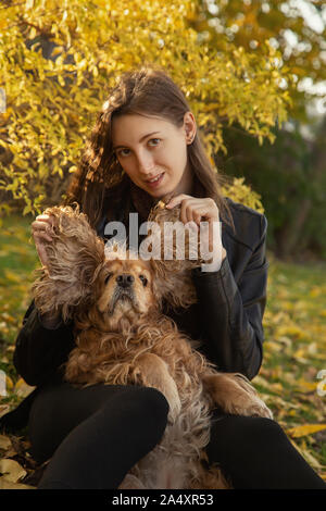 Femme avec cocker américain joue à autumn park Banque D'Images