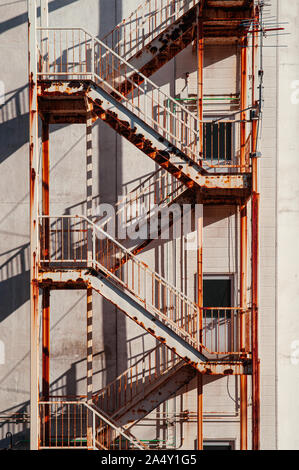 Old rusty metal avec la sortie d'urgence de l'immeuble vue depuis l'escalier de fer à l'extérieur du bâtiment sous la lumière du soleil forte Banque D'Images