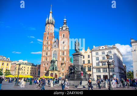 Les touristes profiter de leur temps à marcher et se promener à la place principale de Cracovie avec Adam Mickiewicz Monument et la Basilique Sainte-Marie en Pologne Banque D'Images