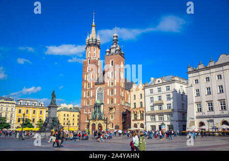 Les touristes profiter de leur temps à marcher et se promener à la place principale de Cracovie avec Adam Mickiewicz Monument et la Basilique Sainte-Marie en Pologne Banque D'Images