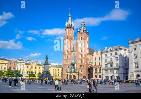 Les touristes profiter de leur temps à marcher et se promener à la place principale de Cracovie avec Adam Mickiewicz Monument et la Basilique Sainte-Marie en Pologne Banque D'Images