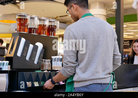 Motion de remplissage des travailleurs du sucre sur table à l'intérieur magasin Starbucks Banque D'Images