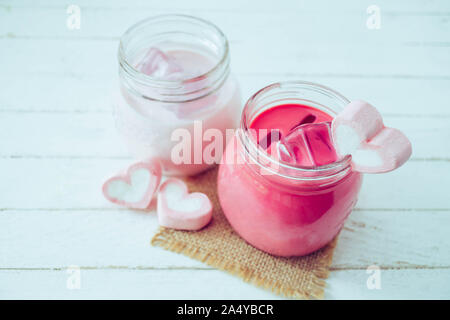 Milkshake rose en forme de coeur avec des guimauves sur fond de bois Banque D'Images