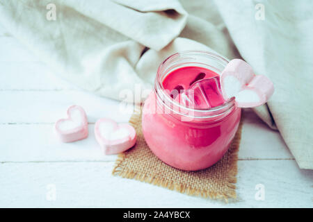 Milkshake rose en forme de coeur avec des guimauves sur fond de bois Banque D'Images
