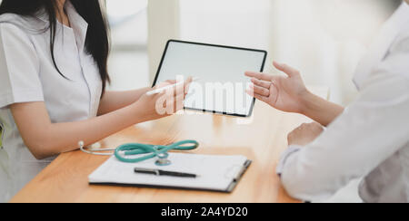 Cropped shot of young female doctor expliquer les symptômes de son patient with digital tablet Banque D'Images