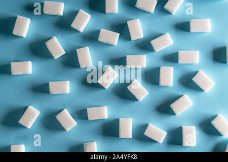 Quelques morceaux de sucre éparpillés sur une surface bleue Banque D'Images