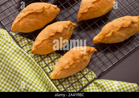 De délicieuses pâtisseries rustiques tartes fraîches avec de la viande et de pommes de terre sur la grille de cuisson en métal. Vue d'en haut. Banque D'Images