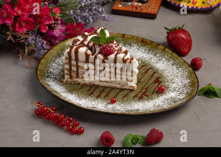 Millefeuille amande amande avec la crème glacée et de baies dans une plaque verte sur fond gris Banque D'Images