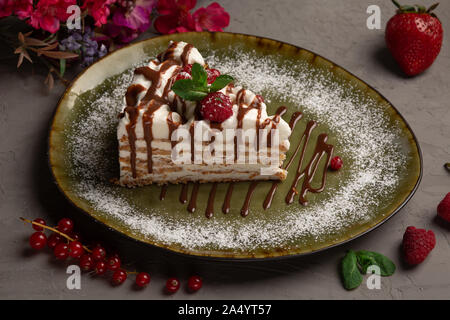 Millefeuille amande amande avec la crème glacée et de baies dans une plaque verte sur fond gris Banque D'Images