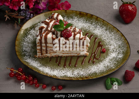 Millefeuille amande amande avec la crème glacée et de baies dans une plaque verte sur fond gris Banque D'Images