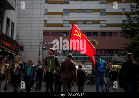 Un homme âgé en uniforme militaire porte un drapeau communiste pour le premier mai 2019 à Berlin, Allemagne Banque D'Images