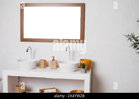 Salle de bains avec deux lavabos. Grand miroir accroché sur le mur blanc. Banque D'Images
