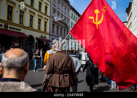 Un homme âgé en uniforme militaire porte un drapeau communiste pour le premier mai 2019 à Berlin, Allemagne Banque D'Images