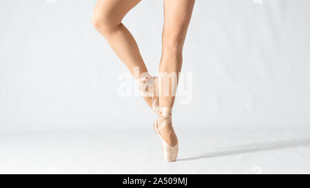 Close-up of dancing les jambes de ballerine wearing white pointe sur un fond blanc. Danseur de Ballet et de l'arrière-plan la notion de pratique Banque D'Images