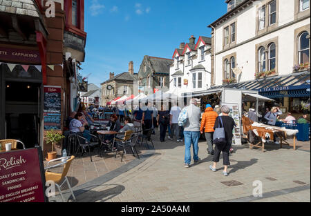 Les touristes les visiteurs marchant le long des stands extérieurs du marché du jeudi à l'été Market Square Keswick Cumbria Angleterre Royaume-Uni Grande-Bretagne Banque D'Images