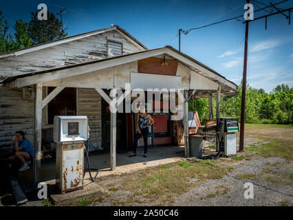 Femme Asiatique avec des lunettes de soleil et les cheveux en chignon et teen girl standing in front of abandoned gas station en Virginie Banque D'Images