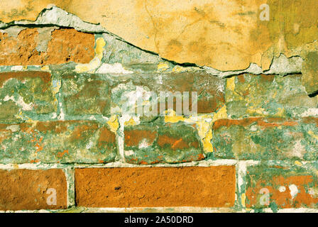 Peinture jaune fissuré, surface de plâtre sur mur de brique rouge avec ombre verte, grunge background minable horizontale détail close up Banque D'Images