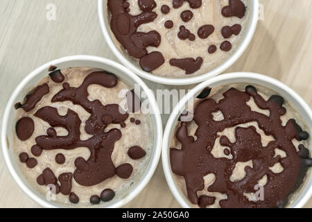 Recette sucrée de délicieux aliments inoffensifs. Close up matières la crème glacée aux fruits de la banane et la crème de coco avec des gouttelettes de chocolat dans un papier blanc Banque D'Images