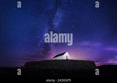 Église St Cwyfans dans la mer de nuit avec la Voie Lactée près de Aberffraw sur l'île d'Anglesey, au Pays de Galles, Royaume-Uni Banque D'Images