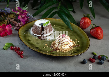 Flan au chocolat et boule de glace dans une assiette verte sur fond gris Banque D'Images