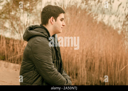 Close-up d'un jeune homme pensif assis dans la nature Banque D'Images